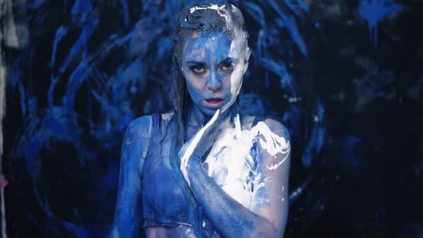 Impassioned, sexy girl touches herself and smearing white and blue paint on a beautiful body. Front view — Stock Video