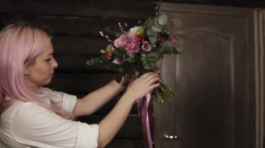 Pembe saçlı bir kız elleri onun önünde çiçek çeşitli tutar. Buket sarkan ipek kurdeleler ile dekore edilmiştir. Yan görünüm