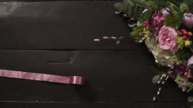 Koyu ahşap yüzeyi, güzel bir buket çiçek bir çerçeve içinde iki ipek pembe kurdeleler yayılmış. Ağır çekim
