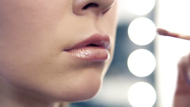 Closeup view of a professional makeup artist applying lipstick on models lips working in beauty salon. Closeup view of an artists hand using special brush — Stock Video