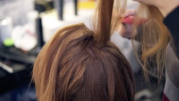 Στυλίστας χτενίζει τα μαλλιά του θηλυκό πελάτη σε επαγγελματική κομμωτήριο. Έννοια της ομορφιάς και περιποίησης μαλλιών — Αρχείο Βίντεο
