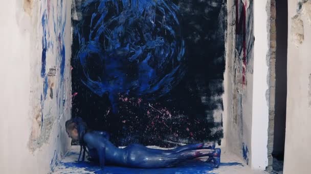 Jovem mulher atraente pintado na cor azul fazendo exercícios na sala colorida. Filmagem frontal — Vídeo de Stock