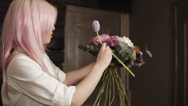 Uma jovem mulher reuniu um deslumbrante buquê de flores, complementa-o com uma tulipa roxa. Fechar quadro de um buquê — Vídeo de Stock
