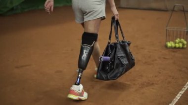 Onun elinde bir spor çanta çekici yaralı kız eğitmek için kapalı Tenis Kortu geliyor. İlk topu hizmet yapma. Ağır çekim