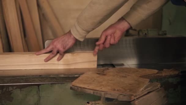 Hombre en overoles pulir y alinear tablas con sierra eléctrica, en un taller de carpintería. Movimiento lento — Vídeo de stock