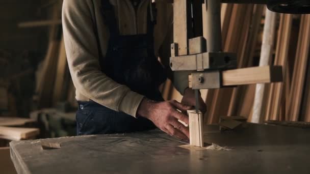 Filmagem em câmera lenta de carpinteiro trabalhando com um bloco de madeira na oficina. Serra eléctrica. Mobiliário de madeira atrás — Vídeo de Stock