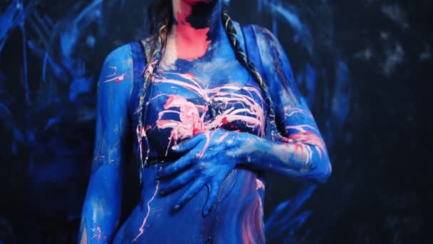 The sexy girl blurs the blue and pink paint erotically on her body, touches herself. Pink paint splash from the side. Slow motion — Stock Video