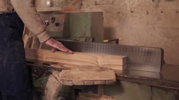 Närbild bilder av man i arbetskläder som arbetar på elektrisk såg med trämaterial i snickeri. Slow motion — Stockvideo