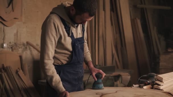 El carpintero en su pequeño taller está trabajando en pulir la pieza de madera. Sander. Apuntar al tiro — Vídeos de Stock