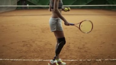 Yan görüntüleri güzel, genç bir kadının bacak protezi rakip Tenis oynarken dönüyoruz. Topu hizmet. Ağır çekim