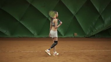 Engelli genç kadın Tenis Kortu raketle yürüyor. Duruş tribünlerde. Maç için hazır