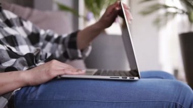 Kulaklıklar ile gülümseyen genç bir kız tarafından açılış belgili tanımlık laptop görüntülerini nişan. Kız Internet üzerinde iletişim başlar. Yazarak. Rahat bir koltukta vardır