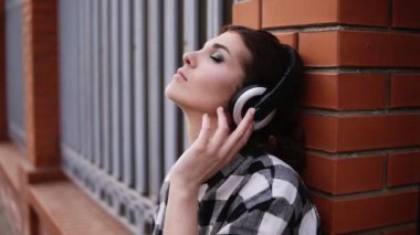 Kadın ikindilerde çit sokaktaki duvara yaslanmış kulaklıklar müzik dinler. Gözlerim kapalı. Makyaj. Yakın çekim