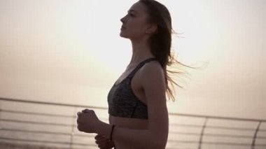 Bir gezinti yerinde kaçan genç sportif kız. Sabah güneş doğuyor. Sahil yolunu. Özgür hissediyorum. Sağlıklı bir yaşam tarzı. İnce beden