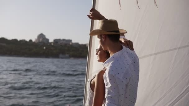 Sailing boat - Romantic young couple enjoying time together on small cruise ship sailing on open sea. Woman and man in love on boat travel sailing during vacation, guy holding a hand of his girlfriend — Stok video