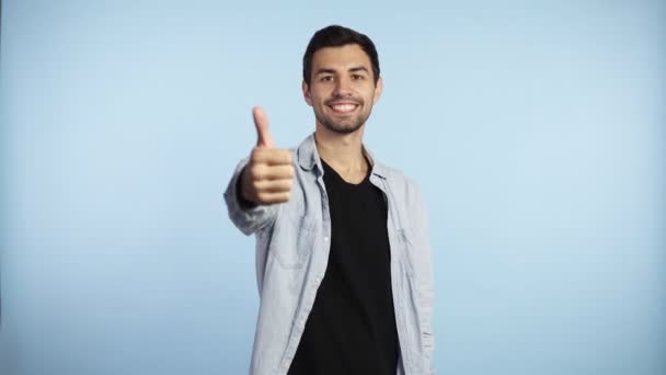 Homem feliz mostra o polegar para cima, homem alegre sorrindo para a câmera. Morena alegre cara, cara de sucesso dando polegar para cima polegar bem sucedido sim ok conceito caucasiano adulto homem modelo no fundo azul — Vídeo de Stock