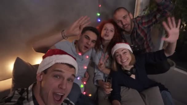Caucasian friends girls and boys together having fun, super excited. Group beautiful young people doing selfie in the new year, posing, looking to the camera. Some wearing santa hats. High angle view — Stok video