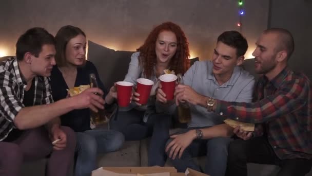 Retrato de diversos grupos de amigos han entregado pizza celebrando - bebiendo alegremente cerveza, salud. Divertida fiesta en acogedora habitación decorada con luces de guirnalda en compañía de amigos cercanos — Vídeos de Stock