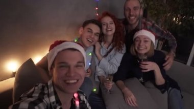 En iyi arkadaşlar kızlar ve erkekler birlikte eğleniyorlar, ellerinde şampanya bardaklarıyla. Yeni yılda selfie çeken, poz veren, kameraya bakan bir grup güzel genç. Bazıları Noel Baba şapkası takıyor.