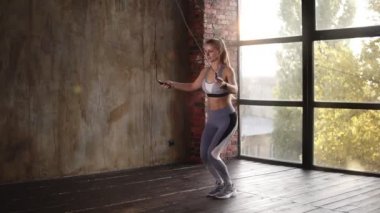Spor salonunda ip atlarken atkuyruklu seksi fitness kadını. Boş stüdyoda ip atlama egzersizi yapan güzel kız. Ciddi bir kadın kardiyo eğitimi alıyor.