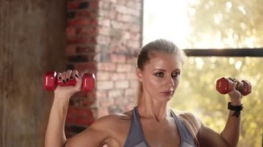 Spor salonunda ya da stüdyoda ağırlık çalışmasıyla egzersiz yapan formda bir kadın. Aktif haldeki fitness mankeni portresi halter bisepsi yapıyor içeride kıvrımlı egzersiz yapıyor