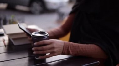 Güzel, genç Müslüman bir kadın hafta sonları bir kafede akıllı telefondan sohbet ediyor ve kahve içiyor. Tesettürlü gülümseyen Müslüman kadın cep telefonu ve kahve fincanıyla mutlu bir şekilde oturuyor.