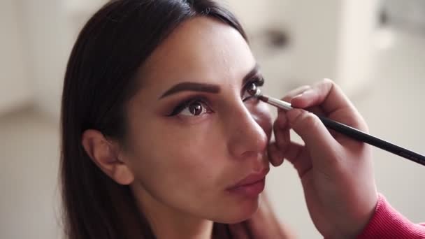 Maquillaje profesional en estudio artístico. Hembra irreconocible maquillaje artista aplicar y mezclar modelos párpado inferior con sombras de ojos. Proceso de creación de ojos ahumados impecables maquillaje mirada — Vídeo de stock