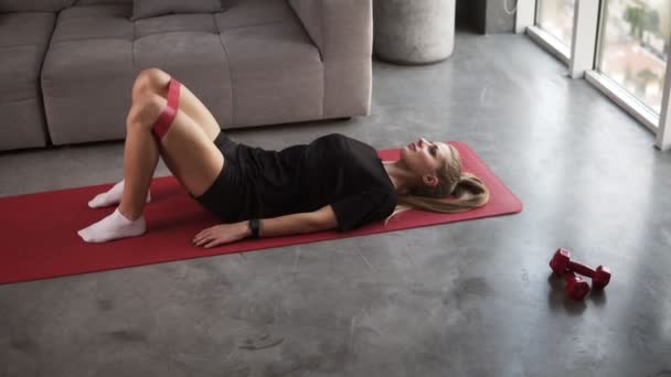 Ellenállás karika banda gyakorlatok. Fit lány edzés a padlón csinál Glute híd elrablása edzés gyakorlat tónusú izmok és aktiválja a fogyás. Loft belső szoba — Stock videók