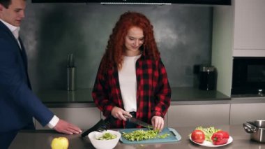 İş dünyasındaki adam, şık takım elbiseli adam işten eve döner ve dikkatli, güzel karısı tarafından bekletilir ve bir akşam yemeği hazırlar. Yakışıklı koca kadınını öper ve ona sarılır. Çatı katı mutfağı.