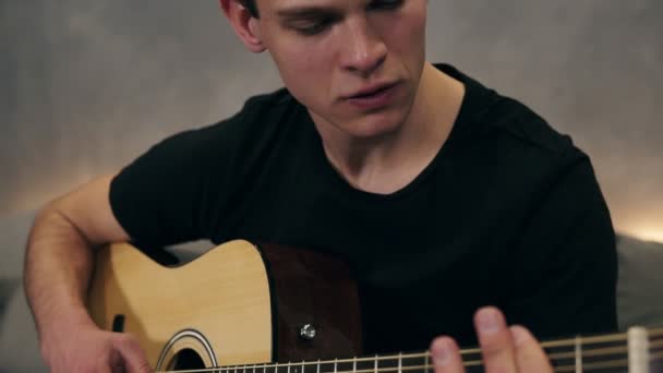 Caucasian guy in black T shirt playing on guitar. Close up of male hands playing on acoustic guitar. Professional guitarist musician playing solo on guitar. Close up of fingers of man musician and — Stock Video