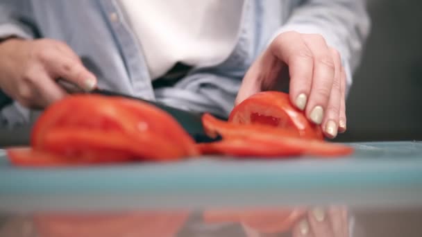 Front view of womans hands slicing fresh red tomatos on cutting board in slow motion. Close up of womans hands with beige manicure preparing vegetables for salad — ストック動画