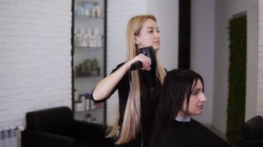 Kafkas esmer genç kadın kuaför salonundaki yeni saç kesiminden önce kuaför berbere saçlarını kurutturdu. Güzellik endüstrisi. Yavaş çekim
