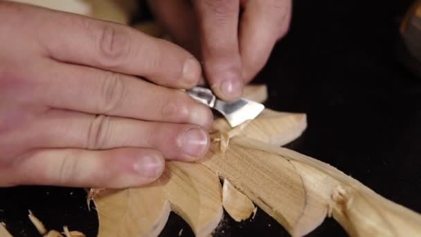 Primer plano de imágenes de las manos de los hombres, que está curvando un pequeño detalle en el patrón de pieza wodden - ornamento floral en el taller de trabajo en la mesa de trabajo con una pequeña cepilladora — Vídeos de Stock