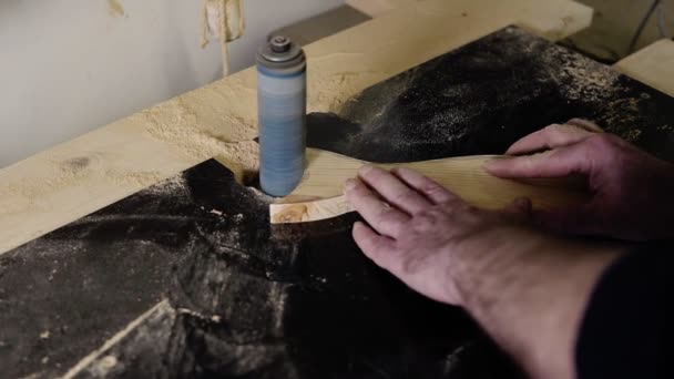 Man grinds the fish tail shape pattern with grinding machine with sawdust flying into the sides, profissão, conceito de carpintaria. Close-up de homem lixar madeira na oficina — Vídeo de Stock