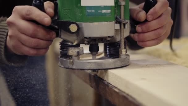 Εξαιρετικά κοντά από ένα craftmans τα χέρια που εργάζονται με τη στίλβωση με το χέρι αλέθοντας μηχανή στο εργαστήριο ξύλου. Αλέθει μια μεγάλη ξύλινη σανίδα. Σκόνη και πατατάκια σκορπίζονται στο πάτωμα. Μη αναγνωρίσιμο — Αρχείο Βίντεο