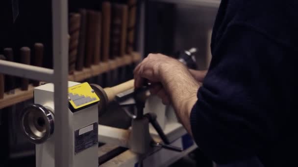 Mãos masculinas do carpinteiro que cortam o botão de madeira fora da peça de madeira que gira na máquina usando o cinzel, trabalhando na forma, decoração. Movimento lento. Vista lateral — Vídeo de Stock