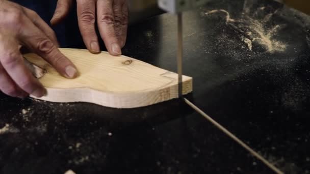 Nahaufnahmen von männlichen Händen, die mit einer elektrischen Schneidemaschine arbeiten. Hochwinkel-Aufnahmen eines Mannes, der ein fischförmiges Holzmuster auf einem Tisch schneidet. Zeitlupe — Stockvideo