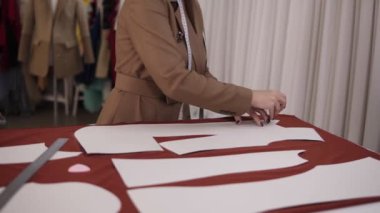 Profesyonel bayan terzi atölyede kırmızı bezle çalışıyor. Yetenekli terzi, kırmızı kumaş üzerine sabunla ya da tebeşirle desenler kullanarak eskiz çiziyor. Kapat.