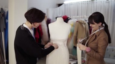 İki profesyonel terzi, tasarımcılar atölyedeki manken üzerine yeni bir elbise dikmeye çalışıyorlar. Kolları düzeltip eteği iğnelemek. Moda ve terzilik konsepti. Yavaş çekim