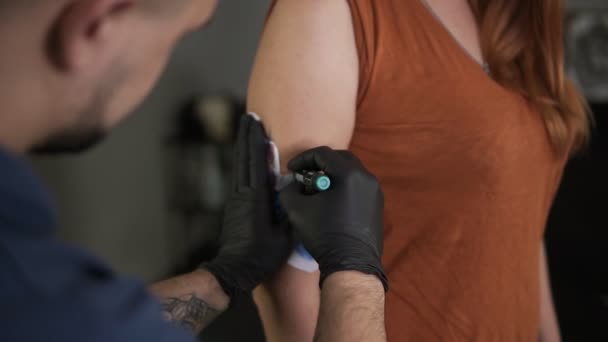 Joven barbudo tatuador dibujo boceto en el brazo de sus clientes mano femenina, bosquejo contorno con rotulador. Inicio de un proceso. De cerca. — Vídeos de Stock