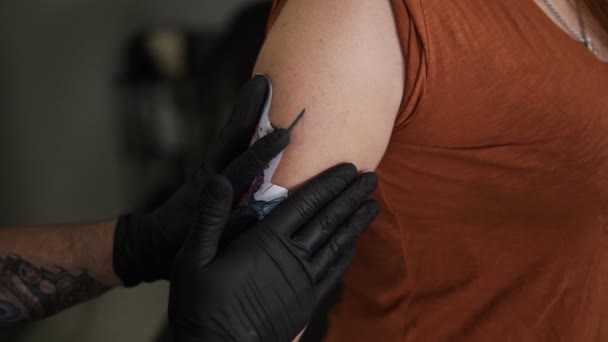 Le tatoueur applique le croquis sur la peau de femme du haut de la main. Essayer d'adapter le croquis coloré sur une cliente méconnaissable, le tenir, attendre jusqu'à ce qu'il colle. Gros plan — Video