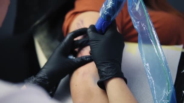 Vrouw tattoo artiest met tattoo pistool, vult het met blauwe inkt, werkt aan handtatoeage. Handschoen hand houden tattoo pistool werken aan moderne body art. Kunstenaar werkt aan wijfjes hand. Langzame beweging — Stockvideo