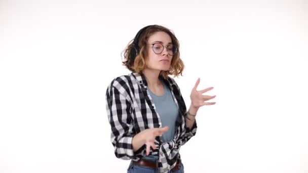 Retrato de la mujer contenta escuchando su canción favorita en el baile y el canto de teléfonos inteligentes mientras disfruta de la música con auriculares sobre fondo blanco. Concepto de emociones — Vídeo de stock