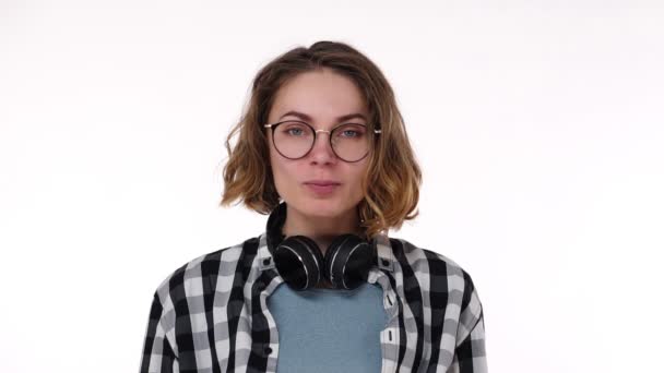 Portrait de jeune fille bouclée sexy ludique vêtue d'une chemise à carreaux debout et isolée sur fond blanc soufflant des bulles de bonbons à la gomme à mâcher et de la gomme à mâcher. Femme regardant la caméra. Mouvement lent — Video