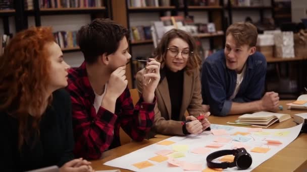 Τέσσερις νεαροί ευρωπαίοι φοιτητές, ομάδα έρευνας μάρκετινγκ που ασχολείται με το επιχειρηματικό σχέδιο εκκίνησης ή το μελλοντικό αλυσοδεμένο έργο. Συζητώντας ενεργά, ακούγοντας ο ένας τον άλλον. Αργή κίνηση — Αρχείο Βίντεο