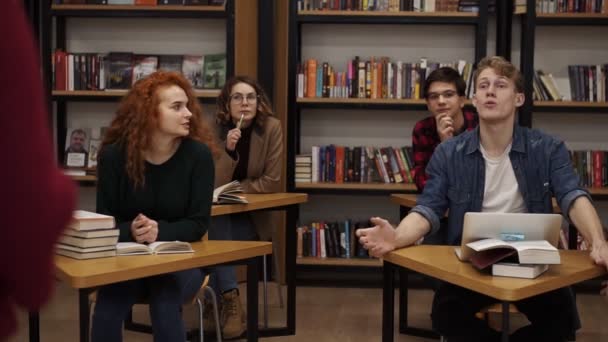 Estudiantes universitarios universitarios europeos estudian juntos preparan proyecto toman notas, jóvenes felices compañeros de clase sentados en las mesas separadas y discuten algo, mirando a la cámara — Vídeo de stock