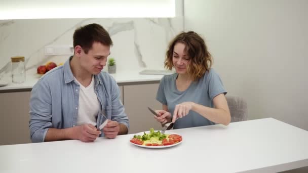 Jong familie paar genieten van ontbijt tijd samen eten omelet van enkele plaat, dagelijkse routine vriendin liefde zorgzame relatie zitten aan bar tafel samen met knappe vriend — Stockvideo