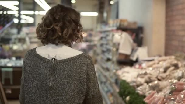 Редкий вид женщины проезжает на тележке через продуктовый отдел в супермаркете и осматривается, собирая мешок с картошкой. Красивые девушки, повседневная жизнь и концепция покупки товаров — стоковое видео