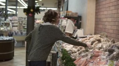 Beyaz bir kadın süpermarkette alışveriş arabasıyla alışveriş yapıyor ve iki torba patates topluyor. Güzel kızlar, günlük hayat ve ürün satın alma kavramı.