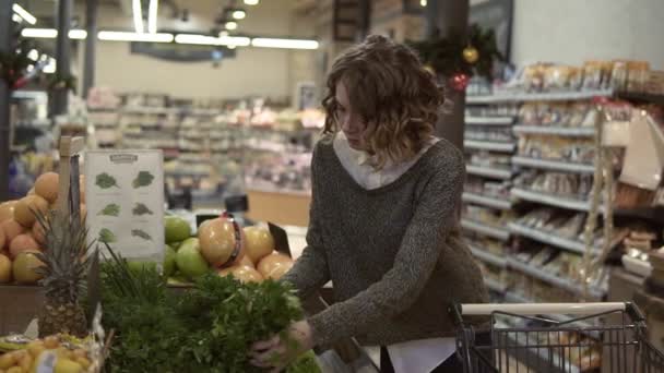 Mladá žena kupuje Ooganic jídlo v supermarketu. Žena bere čerstvou zelenou petržel v obchodě. Vybíráš si dobře bledou. Zpomal. Koncepce zdravého životního stylu — Stock video